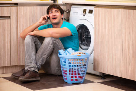 Young husband man doing laundry at homeの写真素材
