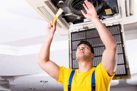 Repairman repairing ceiling air conditioning unitの写真素材