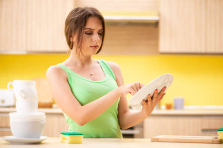 Young woman cleaning and washing dishes in kitchenの写真素材