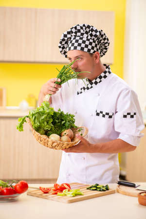 Young professional cook preparing salad at kitchenの写真素材
