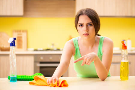 Young beatifull woman polishing table in the kitchen
