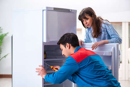 Man repairing fridge with customerの写真素材
