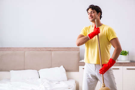 Young handsome man cleaning in the bedroomの写真素材