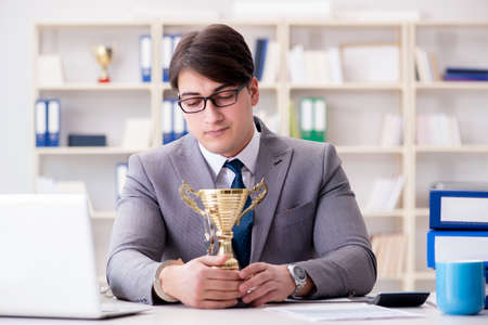 Businessman with golden cup in the officeの写真素材