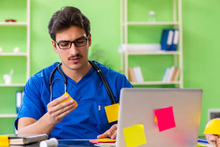 Young doctor sitting in hospital with many conflicting prioritie