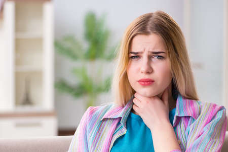 Young woman suffering from sore throat pain