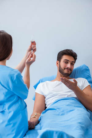 Woman doctor examining male patient in hospitalの写真素材