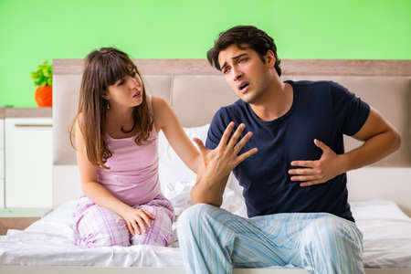 Young husband having problems with health in bedroomの写真素材