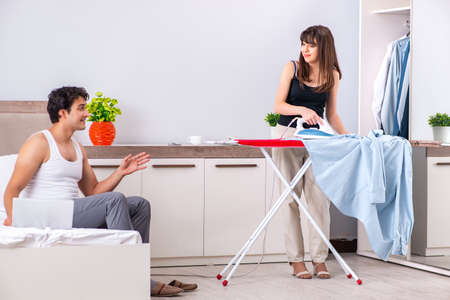 Young woman doing ironing for her husbandの写真素材