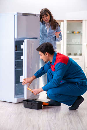 Man repairing fridge with customerの写真素材