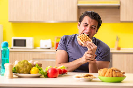 Man having hard choice between healthy and unhealthy foodの写真素材