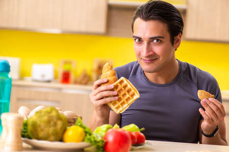 Man having hard choice between healthy and unhealthy foodの写真素材