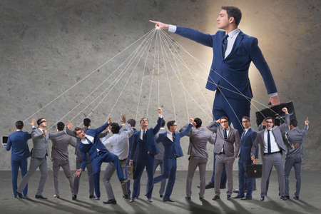 Boss employee manipulating his staff in business conceptの写真素材