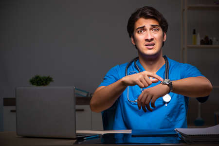 Young handsome doctor working night shift in hospitalの写真素材