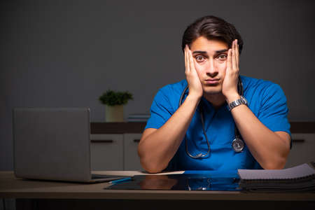 Young handsome doctor working night shift in hospitalの写真素材