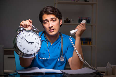 Young handsome doctor working night shift in hospitalの写真素材