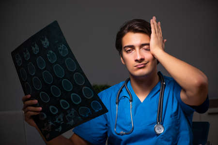 Young handsome doctor working night shift in hospitalの写真素材