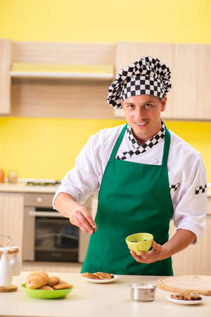 Young man cook preparing cake in kitchen at homeの写真素材