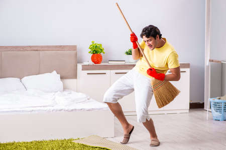 Young handsome man cleaning in the bedroomの写真素材