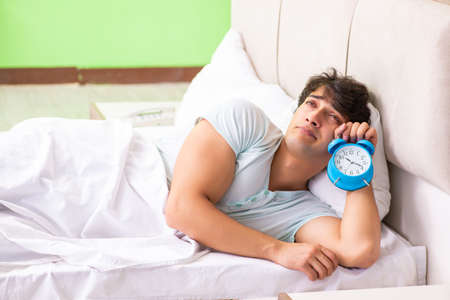 Young man having trouble waking up in early morningの写真素材