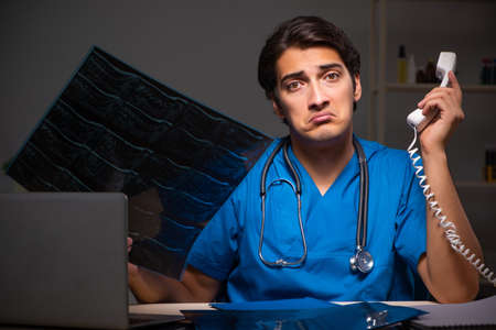 Young handsome doctor working night shift in hospitalの写真素材