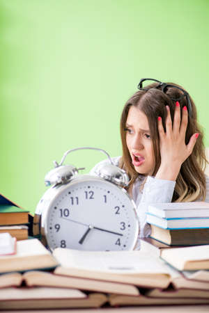Young female student preparing for exams with many books in timeの写真素材