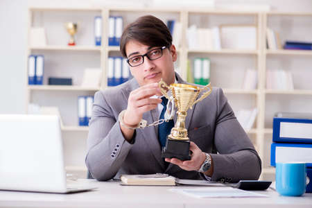 Businessman with golden cup in the officeの写真素材