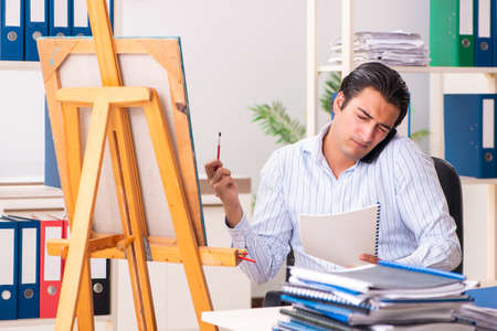 Young handsome employee enjoying painting at the officeの写真素材