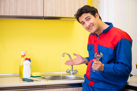 Plumber repairing tap at kitchenの写真素材