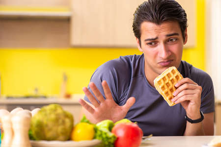 Man having hard choice between healthy and unhealthy foodの写真素材