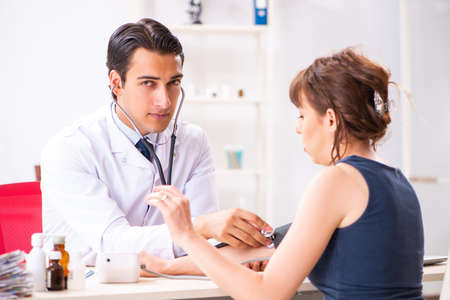 Young doctor checking womans blood pressureの写真素材