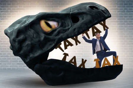 Businessman in the jaws of high taxesの写真素材