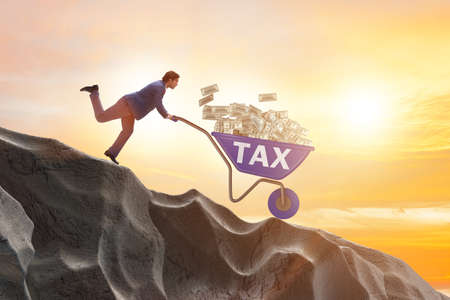 Businessman pushing wheelbarrow with tax moneyの写真素材