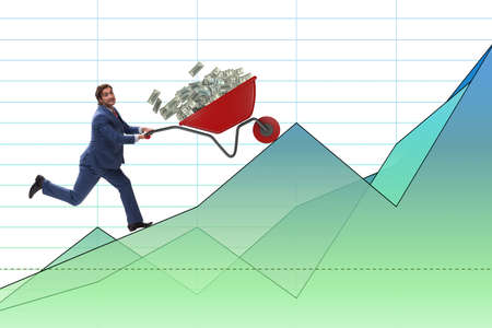Businessman pushing wheelbarrow full of dollar moneyの写真素材