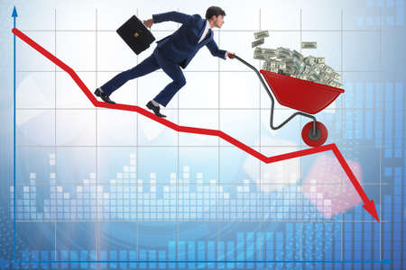 Businessman pushing money wheelbarrow down the chartの写真素材