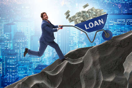 Businessman pushing wheelbarrow uphill in debt loan concept