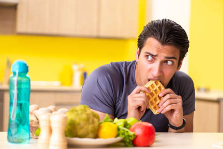 Man having hard choice between healthy and unhealthy foodの写真素材