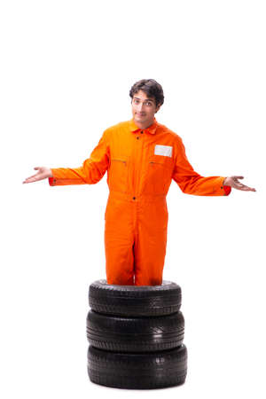 Young garage worker with tyre isolated on whiteの写真素材