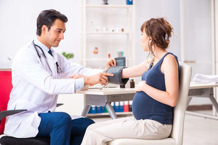 Young doctor checking pregnant womans blood pressureの写真素材