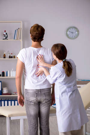 Male patient visiting young female doctor chiropractorの写真素材