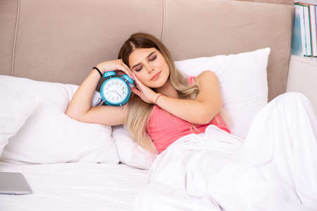 Young woman waking up in the morning in bedの写真素材