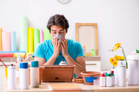 Young man decorating pottery in classの写真素材