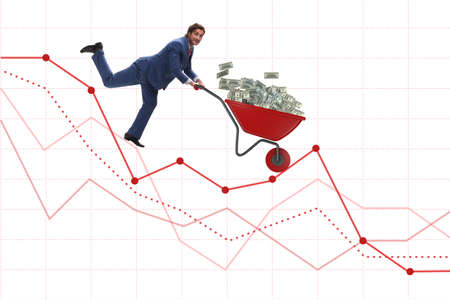 Businessman pushing money wheelbarrow down the chartの写真素材