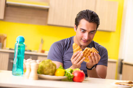 Man having hard choice between healthy and unhealthy foodの写真素材