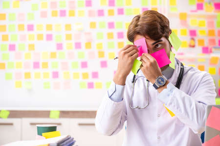 Male doctor with many conflicting priorititesの写真素材