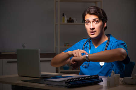 Young handsome doctor working night shift in hospitalの写真素材