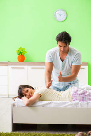 Man doing massage to his wife in bedroomの写真素材