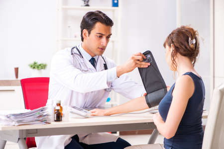 Young doctor checking womans blood pressureの写真素材