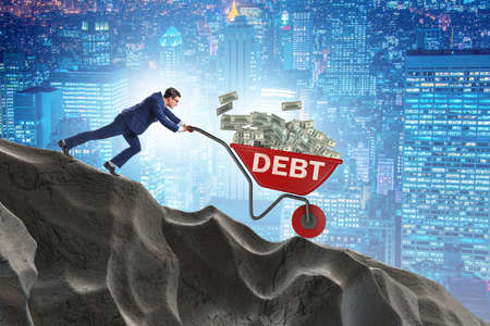 Businessman pushing wheelbarrow with dollars downhillの写真素材
