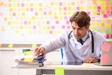 Male doctor with many conflicting priorititesの写真素材